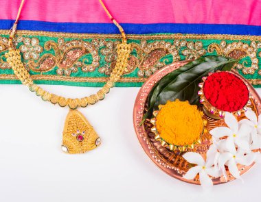 Mangalsutra or Golden Necklace to wear by a married hindu women, arranged with traditional saree with haldi, kumkum and flowers on plate.