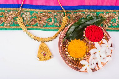 Mangalsutra or Golden Necklace to wear by a married hindu women, arranged with traditional saree with haldi, kumkum and flowers on plate.