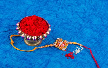 Indian Festival Rakhi with rice grains, kumkum on background with an elegant Rakhi. A traditional Indian wrist band which is a symbol of love between Brothers and Sisters.