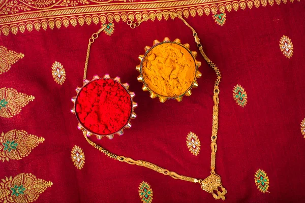 Mangalsutra or Golden Necklace to wear by a married hindu women, arranged with traditional saree with haldi, kumkum and grain rice on plate. Indian Traditional Jewellery.