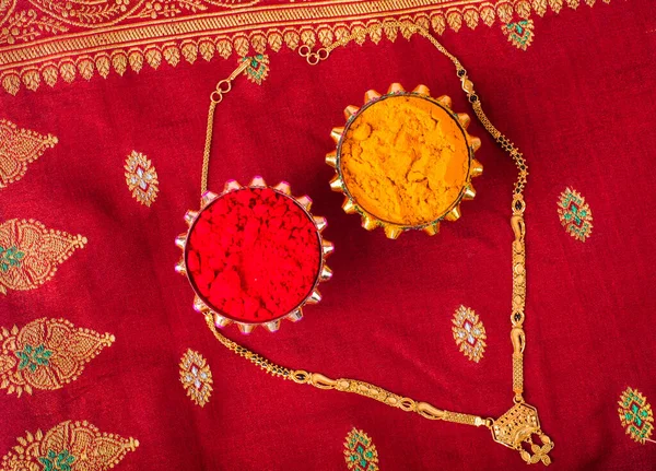 Mangalsutra or Golden Necklace to wear by a married hindu women, arranged with traditional saree with haldi, kumkum and grain rice on plate. Indian Traditional Jewellery.