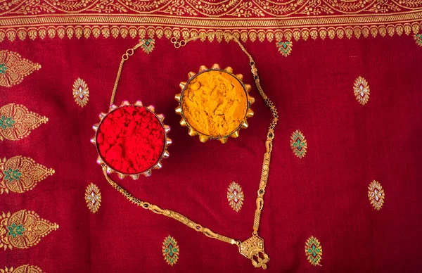 Mangalsutra or Golden Necklace to wear by a married hindu women, arranged with traditional saree with haldi, kumkum and grain rice on plate. Indian Traditional Jewellery.