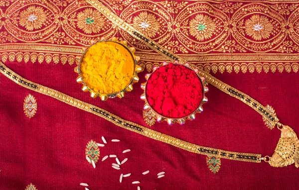 Mangalsutra or Golden Necklace to wear by a married hindu women, arranged with traditional saree with haldi, kumkum and grain rice on plate. Indian Traditional Jewellery.