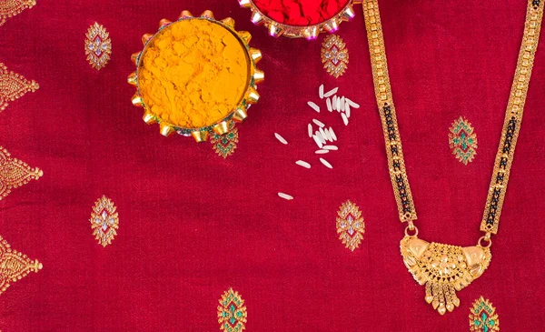 Mangalsutra or Golden Necklace to wear by a married hindu women, arranged with traditional saree with haldi, kumkum and grain rice on plate. Indian Traditional Jewellery.