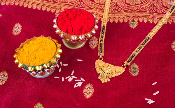 Mangalsutra or Golden Necklace to wear by a married hindu women, arranged with traditional saree with haldi, kumkum and grain rice on plate. Indian Traditional Jewellery.