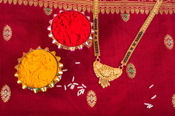 Mangalsutra or Golden Necklace to wear by a married hindu women, arranged with traditional saree with haldi, kumkum and grain rice on plate. Indian Traditional Jewellery.
