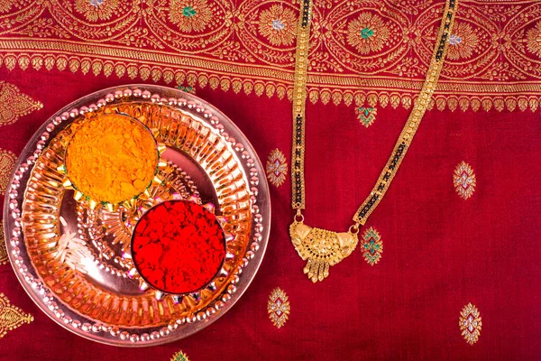 Mangalsutra or Golden Necklace to wear by a married hindu women, arranged with traditional saree with haldi, kumkum and grain rice on plate. Indian Traditional Jewellery.