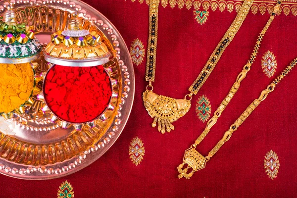 Mangalsutra or Golden Necklace to wear by a married hindu women, arranged with traditional saree with haldi, kumkum and grain rice on plate. Indian Traditional Jewellery.