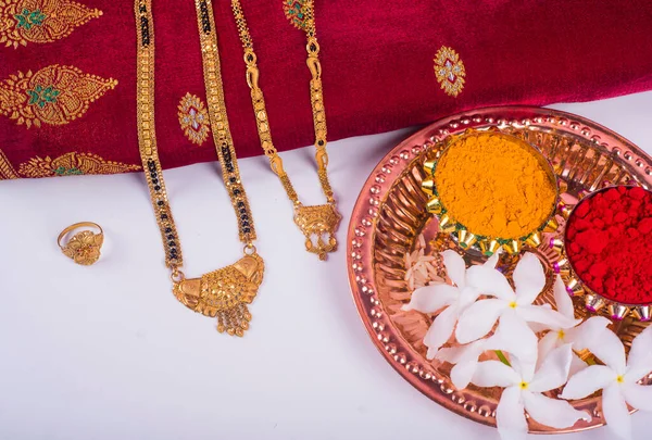 Mangalsutra or Golden Necklace to wear by a married hindu women, arranged with traditional saree with haldi, kumkum and flowers on plate