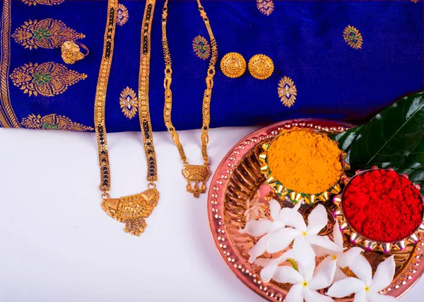 Mangalsutra or Golden Necklace to wear by a married hindu women, arranged with traditional saree with haldi, kumkum and flowers on plate
