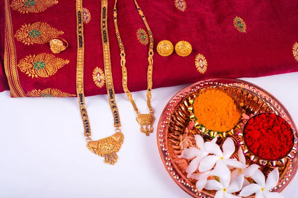 Mangalsutra or Golden Necklace to wear by a married hindu women, arranged with traditional saree with haldi, kumkum and flowers on plate