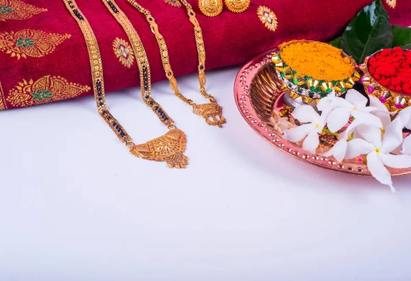 Mangalsutra or Golden Necklace to wear by a married hindu women, arranged with traditional saree with haldi, kumkum and flowers on plate