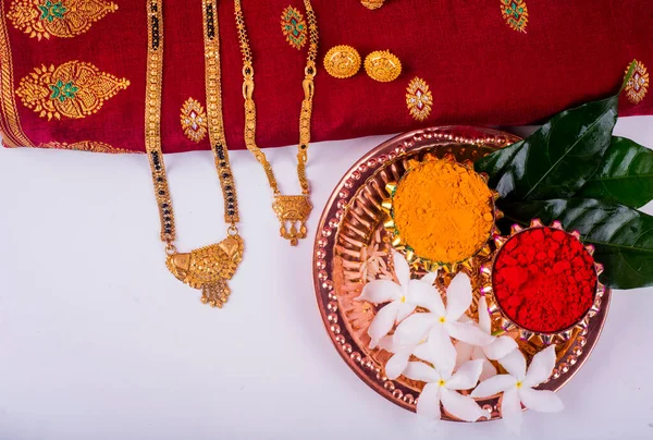 Mangalsutra or Golden Necklace to wear by a married hindu women, arranged with traditional saree with haldi, kumkum and flowers on plate