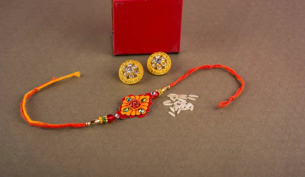 Raakhi with rice grains,kumkum and beautiful earrings gift for the sister given by brother on the occasion of Raksha Bandhan.A traditional Indian wrist band which is festival for brothers and sisters