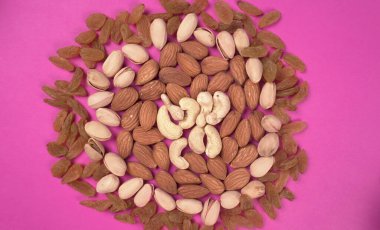 Variety mix of dried fruits and nuts on a pink background. Concept of Healthy fitness super food