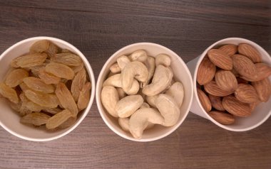 Variety mix of dried fruits and nuts in bowls on wooden background. Concept of Healthy fitness super food
