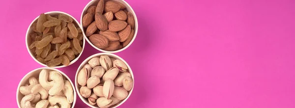 A variety mix of dried fruits and nuts on a pink background. Concept of Healthy fitness super food