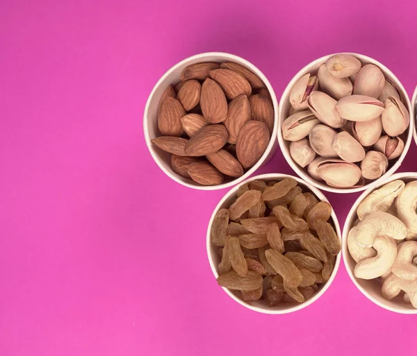A variety mix of dried fruits and nuts on a pink background. Concept of Healthy fitness super food