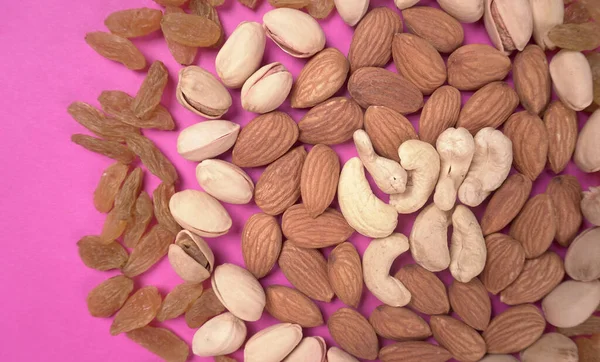 Variety mix of dried fruits and nuts on a pink background. Concept of Healthy fitness super food