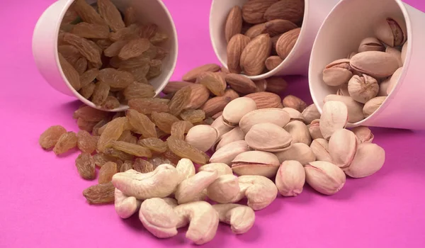 A variety mix of dried fruits and nuts on a pink background. Concept of Healthy fitness super food