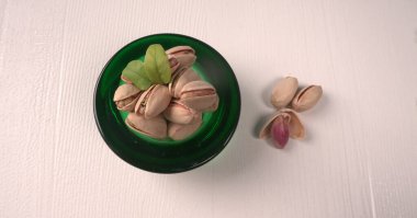 Pistachios in bowl on white background