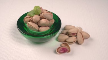 Pistachios in bowl on white background
