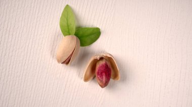 Heap of pistachios with green leaves on white background