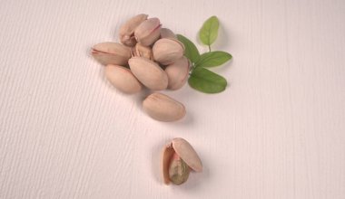 Heap of pistachios with green leaves on white background