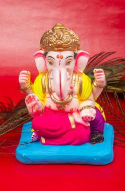 Kırmızı arka planda tavus kuşu tüyü olan güzel Ganesha Hindu heykeli