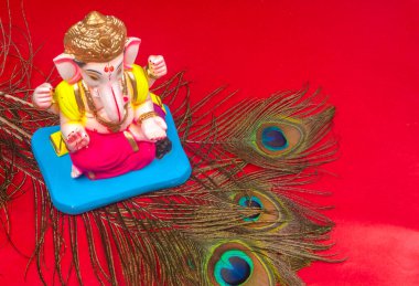 Kırmızı arka planda tavus kuşu tüyü olan güzel Ganesha Hindu heykeli