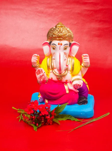 Kırmızı arka planda çiçekler olan güzel Ganesha Hindu heykeli