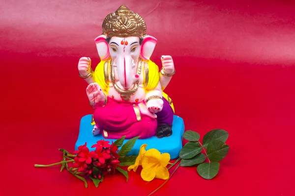 Kırmızı arka planda çiçekler olan güzel Ganesha Hindu heykeli