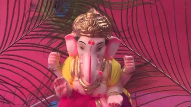 Kırmızı arka planda tavus kuşu tüyleri olan Ganesha Hindu heykeli