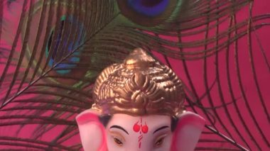 Kırmızı arka planda tavus kuşu tüyleri olan Ganesha Hindu heykeli