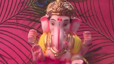 Kırmızı arka planda tavus kuşu tüyleri olan Ganesha Hindu heykeli