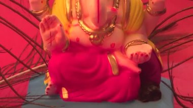 Kırmızı arka planda tavus kuşu tüyleri olan Ganesha Hindu heykeli