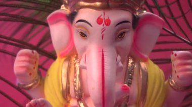 Kırmızı arka planda tavus kuşu tüyleri olan Ganesha Hindu heykeli