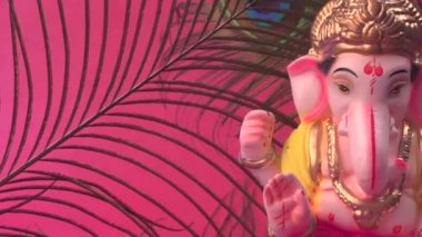 Kırmızı arka planda tavus kuşu tüyleri olan Ganesha Hindu heykeli