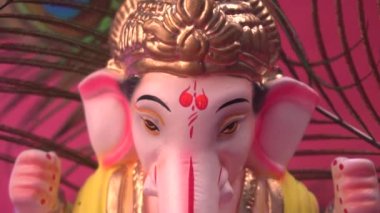 Kırmızı arka planda tavus kuşu tüyleri olan Ganesha Hindu heykeli