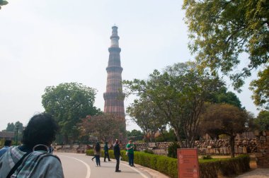 DELHI, Hindistan - 23 Şubat 2018: Kutub Minar 'ı ziyaret eden kimliği belirsiz kişiler, Hindistan' ın en uzun minaresi bir mermer ve kırmızı kumtaşı kulesidir. 