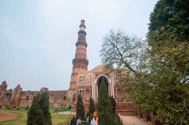 DELHI, Hindistan - 23 Şubat 2018: Kutub Minar 'ı ziyaret eden kimliği belirsiz kişiler, Hindistan' ın en uzun minaresi bir mermer ve kırmızı kumtaşı kulesidir. 