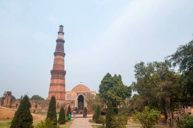 DELHI, Hindistan - 23 Şubat 2018: Kutub Minar 'ı ziyaret eden kimliği belirsiz kişiler, Hindistan' ın en uzun minaresi bir mermer ve kırmızı kumtaşı kulesidir. 