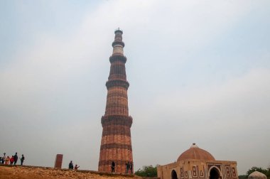 DELHI, Hindistan - 23 Şubat 2018: Kutub Minar 'ı ziyaret eden kimliği belirsiz kişiler, Hindistan' ın en uzun minaresi bir mermer ve kırmızı kumtaşı kulesidir. 
