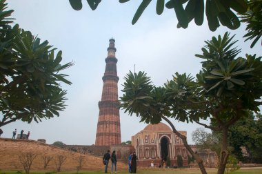 DELHI, Hindistan - 23 Şubat 2018: Kutub Minar 'ı ziyaret eden kimliği belirsiz kişiler, Hindistan' ın en uzun minaresi bir mermer ve kırmızı kumtaşı kulesidir. 