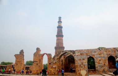 DELHI, Hindistan - 23 Şubat 2018: Kutub Minar 'ı ziyaret eden kimliği belirsiz kişiler, Hindistan' ın en uzun minaresi bir mermer ve kırmızı kumtaşı kulesidir. 