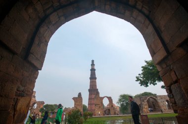 DELHI, Hindistan - 23 Şubat 2018: Kutub Minar 'ı ziyaret eden kimliği belirsiz kişiler, Hindistan' ın en uzun minaresi bir mermer ve kırmızı kumtaşı kulesidir. 