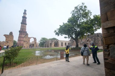 DELHI, Hindistan - 23 Şubat 2018: Kutub Minar 'ı ziyaret eden kimliği belirsiz kişiler, Hindistan' ın en uzun minaresi bir mermer ve kırmızı kumtaşı kulesidir. 