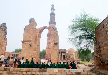 DELHI, Hindistan - 23 Şubat 2018: Kutub Minar 'ı ziyaret eden kimliği belirsiz kişiler, Hindistan' ın en uzun minaresi bir mermer ve kırmızı kumtaşı kulesidir. 