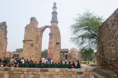 DELHI, Hindistan - 23 Şubat 2018: Kutub Minar 'ı ziyaret eden kimliği belirsiz kişiler, Hindistan' ın en uzun minaresi bir mermer ve kırmızı kumtaşı kulesidir. 