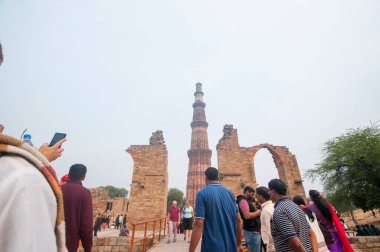 DELHI, Hindistan - 23 Şubat 2018: Kutub Minar 'ı ziyaret eden kimliği belirsiz kişiler, Hindistan' ın en uzun minaresi bir mermer ve kırmızı kumtaşı kulesidir. 